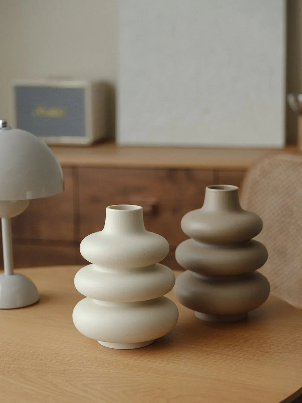 Large ceramic donut-shaped vases with glossy finish on wooden table in modern interior