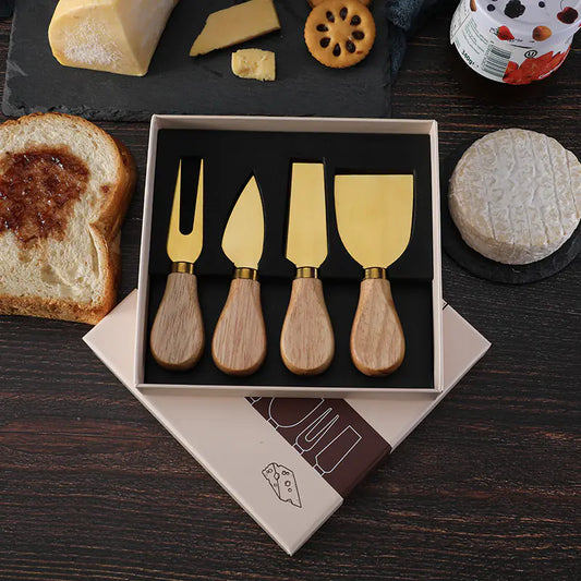 Cheese knife set with oak handles and stainless steel blades in gift box on wooden table with cheese and bread