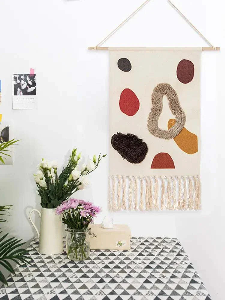 Handcrafted woven tapestry wall hanging with geometric abstraction and tassels, adding Nordic charm to cozy spaces.