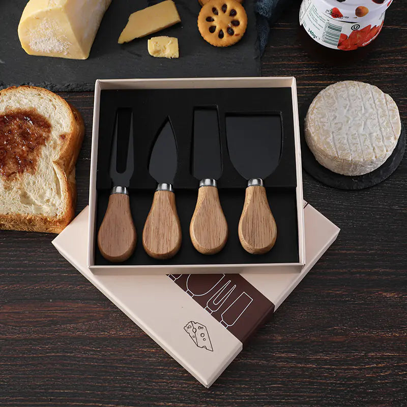 Cheese knife set with stainless steel blades and oak handles in gift box on wooden table with cheese, bread, and crackers