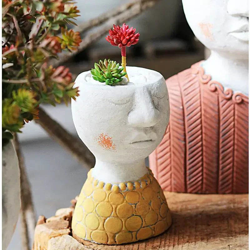Artistic Portrait Sculpture planter with face design, holding small succulents in a yellow textured base.