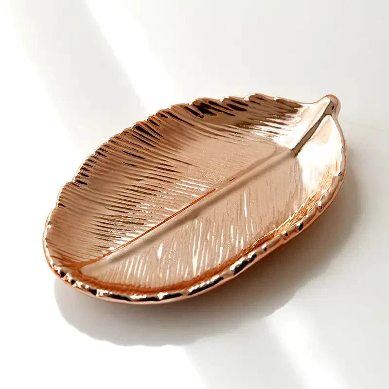 Gold ceramic jewelry tray shaped like a leaf with detailed vein design and high-gloss finish