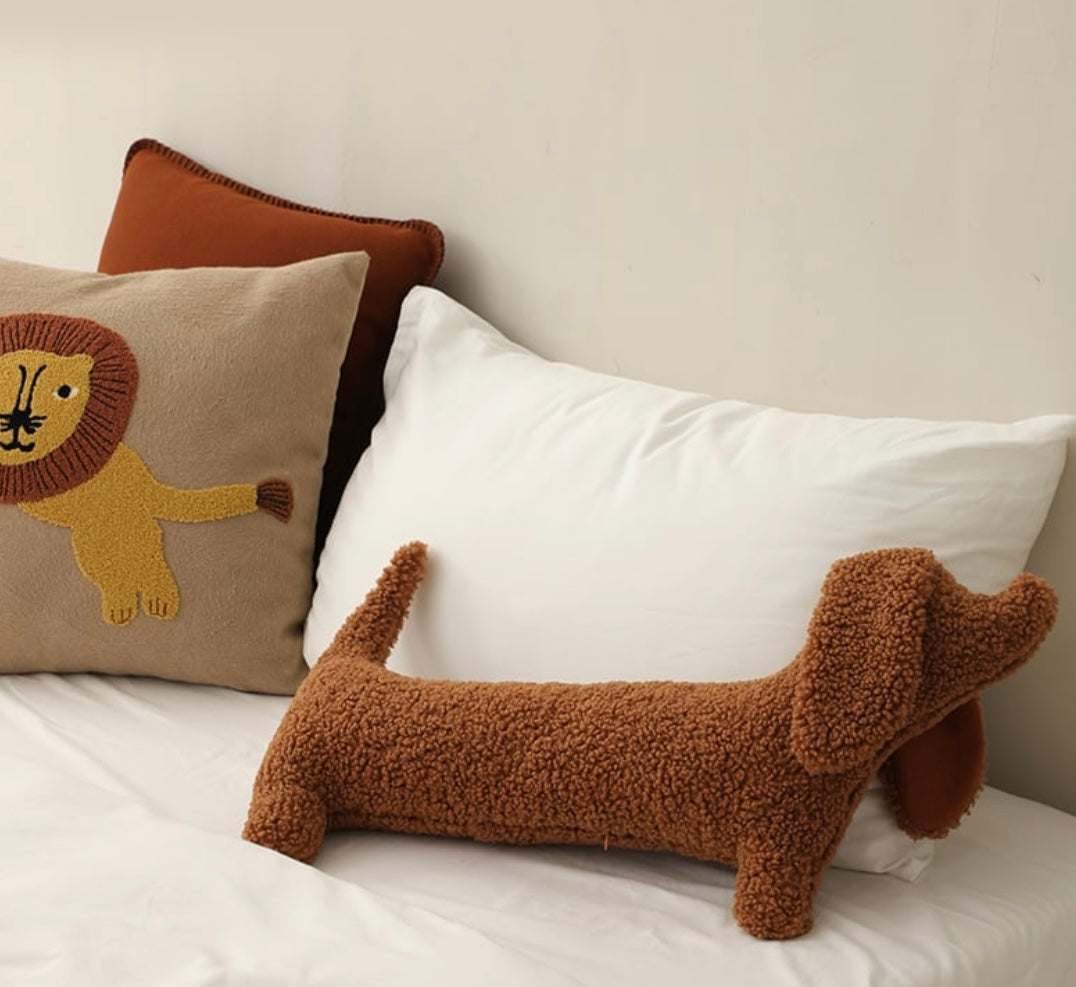 Brown cute plush dachshund pillow with soft textured fabric on white bed with decorative lion pillow