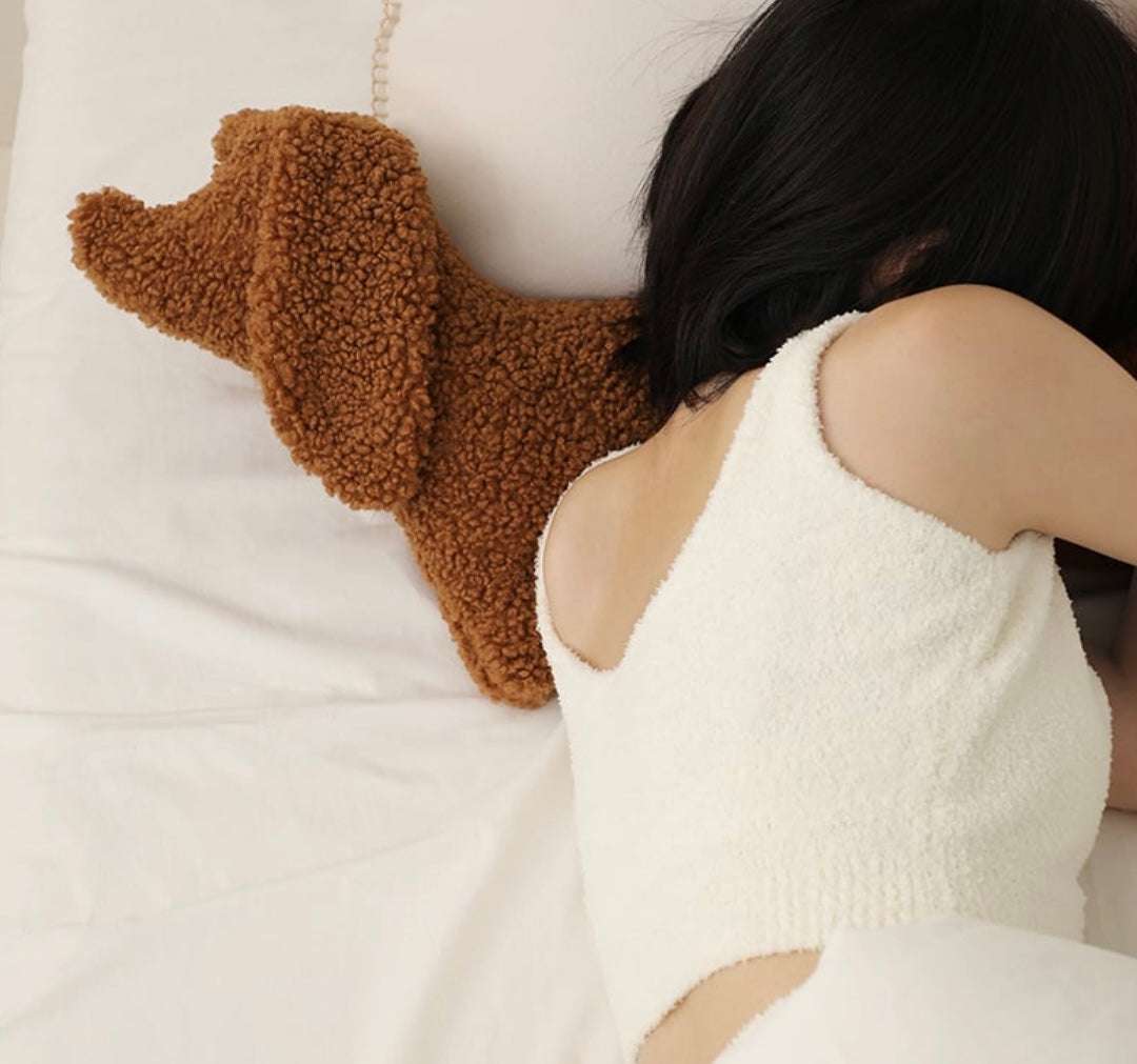 Brown cute plush dachshund pillow made of soft material used as a cozy waist support pillow on a bed
