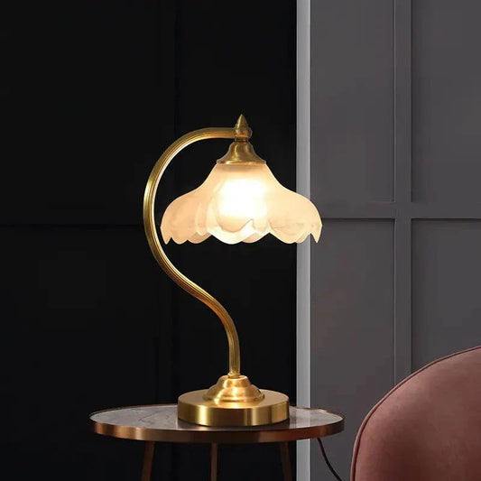 American-style copper decorative table lamp with curved arm and frosted glass shade on a round wooden table