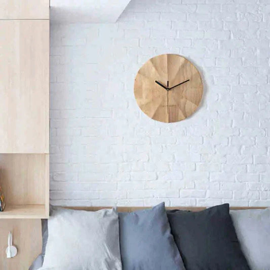 Nordic minimalist wooden wall clock with a 30cm diameter, natural wood finish, and black hands mounted on a white brick wall above a sofa with gray and blue cushions.