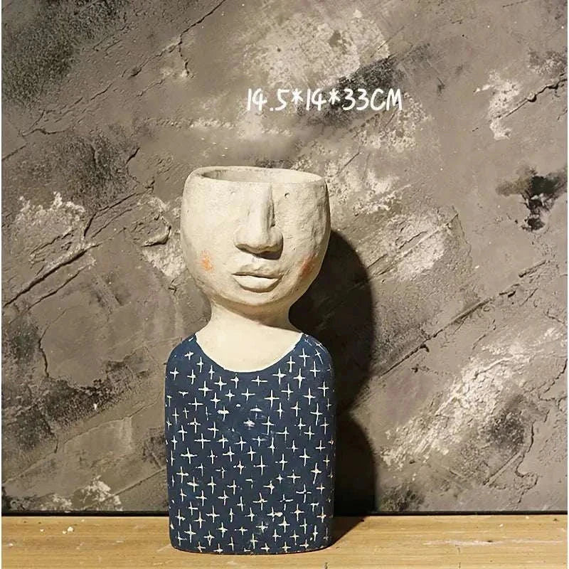 Artistic Portrait Sculpture planter in blue patterned dress with neutral face planter pot on wooden surface against textured wall