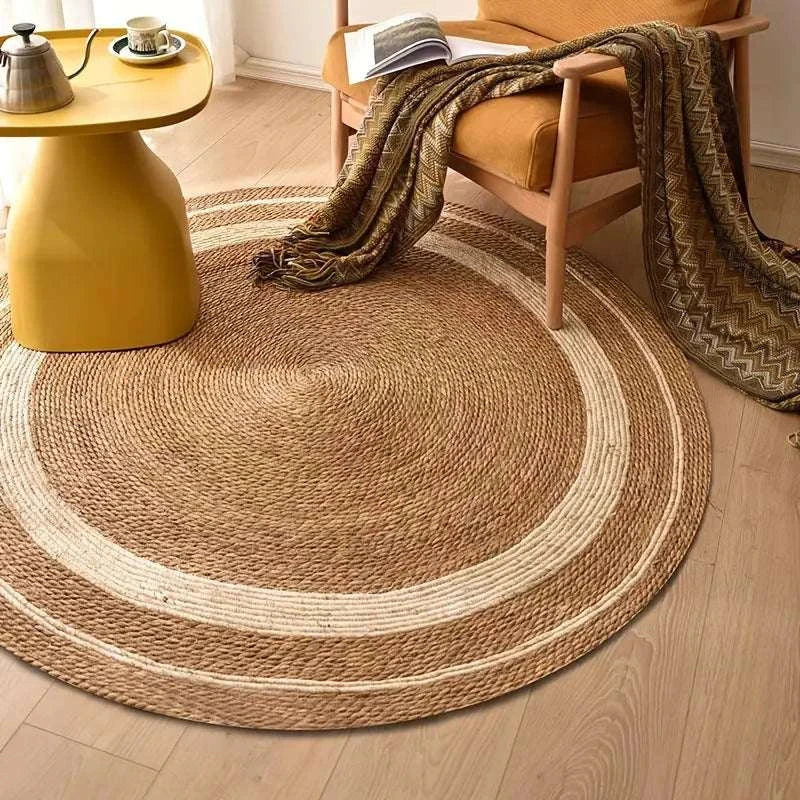 Round Nordic style woven carpet in natural rattan with papyrus color accents on wooden floor.