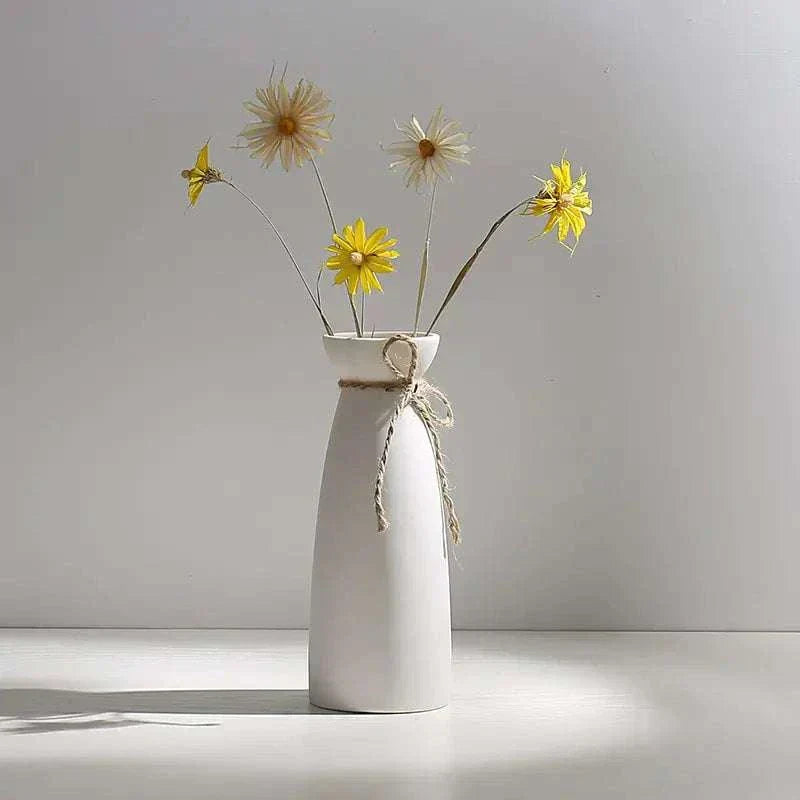 White hemp rope ceramic vase with yellow flowers on a white surface against a light gray background